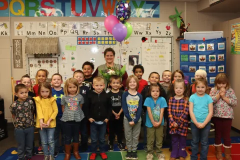 A teacher posing for a picture with her classroom of young students